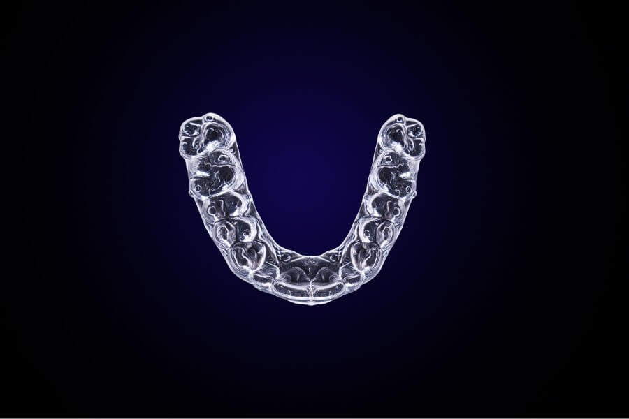 Aerial view of Invisalign clear aligners on a dark blue background in Lytle, TX